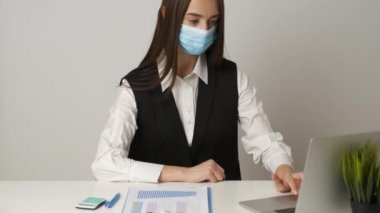 Coronavirus salgını sırasında işyerini korumak ve onunla ilgilenmek için tıbbi maske takan kadın ofis çalışanı. Coronavirus 2019-nCoV konsepti