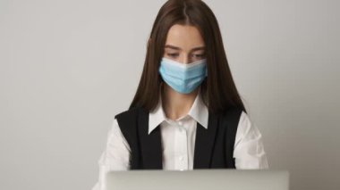 Salgın sırasında sağlıklı iş yerini korumak ve bakımını sağlamak için tıbbi maske takan kadın ofis çalışanının portresi.