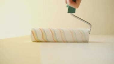 Usta beyaz bir silindirle bir duvar boyuyor. Ofis yenileme ve yenileme. Alt açıdan portre