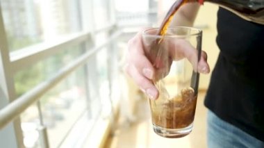 Ofis çalışanı panoramik pencerelerin arka planına soda dolduruyor.