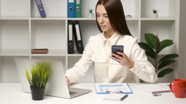 Krásná žena právník pracuje za stolem a řešení jejích pracovních otázek na telefonu při pohledu na notebook — Stock video