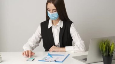 Coronavirus salgını sırasında işyerini korumak ve onunla ilgilenmek için tıbbi maske takan kadın ofis çalışanı. Coronavirus 2019-nCoV konsepti