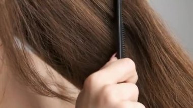 25 yaşında bir esmer, banyoda aynanın önünde duruyor ve ince saçlarını tarıyor. Saç bakımı