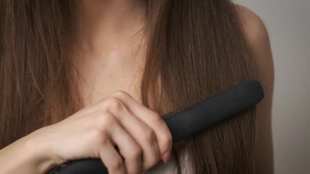 Η όμορφη γυναίκα ισιώνει τα μακριά μαλλιά της. Φροντίδα μαλλιών — Αρχείο Βίντεο