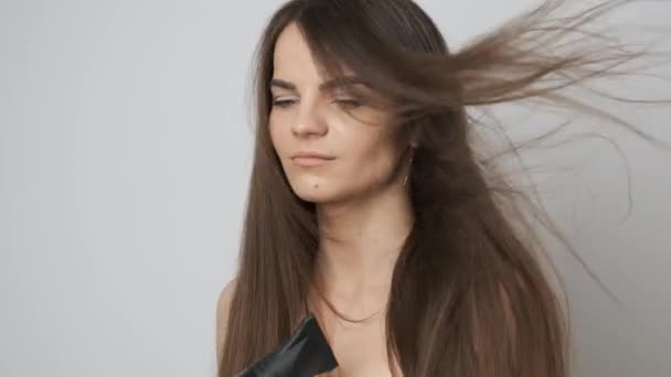Um lindo secador de cabelo no banheiro seca seu longo cabelo escuro — Vídeo de Stock