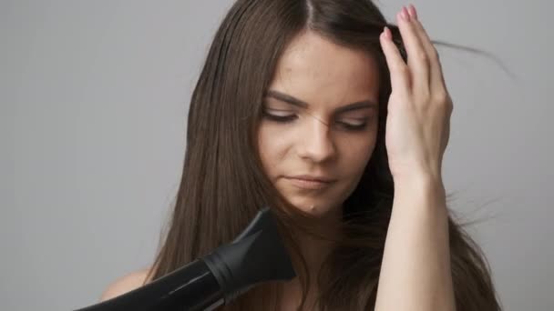 Um lindo secador de cabelo no banheiro seca seu longo cabelo escuro — Vídeo de Stock