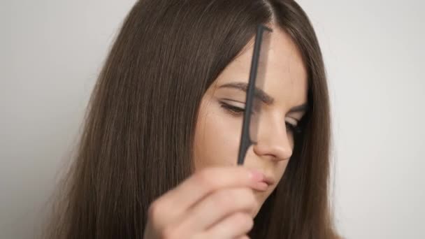 Mujer caucásica peinando su largo cabello castaño-negro en su baño y notando cómo se cae — Vídeo de stock