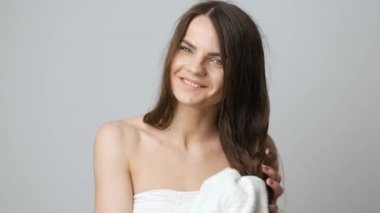 Banyoda esmer bir kadın aynanın önünde duruyor ve ıslak saçlarını havluyla siliyor.