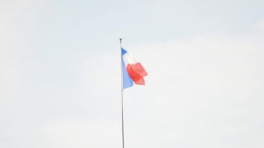 Mavi gökyüzünün arka planında rüzgarlı havada Fransa bayrağı