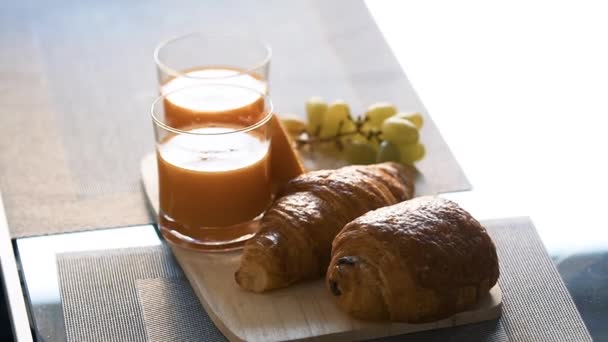 Ochtend sinaasappelsap met croissants en druiven. Ontbijt — Stockvideo