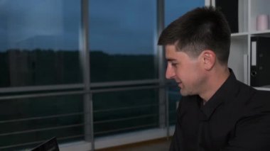 Kafkas görünümlü genç yakışıklı laptopta yazı yazmak iş sorunlarını çözüyor. Gece yönettim.
