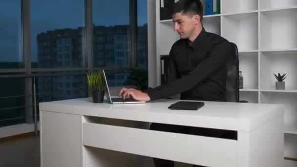 年轻英俊的白种人男子在笔记本电脑上的桌上打字，解决了工作问题。夜间管理 — 图库视频影像