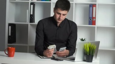 Keskin gözlü bir ofis çalışanı parayı sayar ve bir deftere yazar. Muhasebeci maaş veriyor.