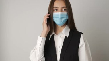 Sündemi sırasında sağlıklı iş yerini korumak ve onunla ilgilenmek için tıbbi maske takan bir kadının portresi. Müdür iş yerinde çalışıyor ve telefonla iletişim kuruyor.