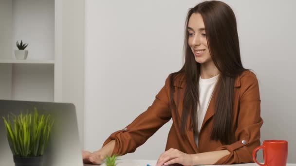 Női barna könyvelő ül az asztalnál dolgozik egy laptop és mosolyogva őszintén — Stock videók