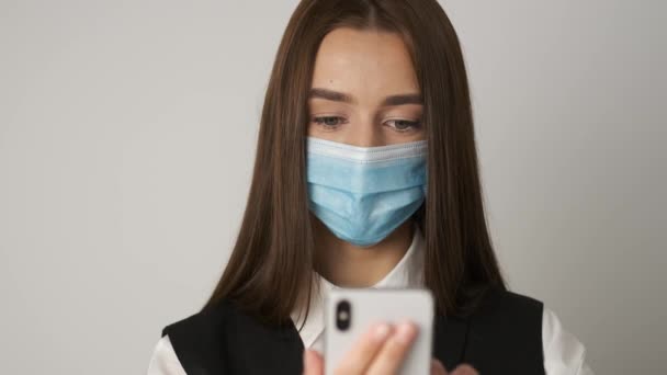 Portret van een vrouw in het kantoor met een medisch masker ter bescherming en verzorging van haar gezonde werkplek tijdens een spondemie. De manager werkt op zijn werkplek en communiceert telefonisch — Stockvideo