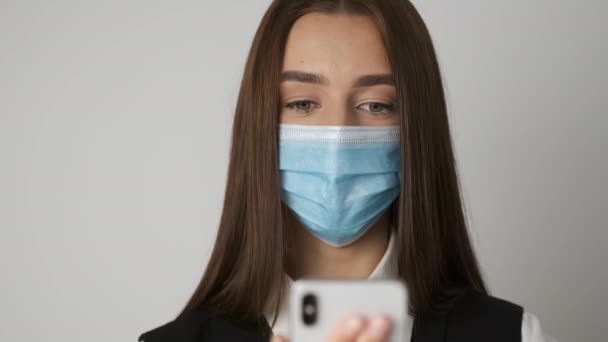 Portret van een vrouw in het kantoor met een medisch masker ter bescherming en verzorging van haar gezonde werkplek tijdens een spondemie. De manager werkt op zijn werkplek en communiceert telefonisch — Stockvideo