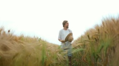 Şapkalı ve sakallı şık Kafkasyalı çiftçi tarlaya buğday tohumları saçıyor.