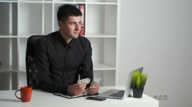 Keskin gözlü bir ofis çalışanı parayı sayar ve bir deftere yazar. Muhasebeci maaş veriyor.