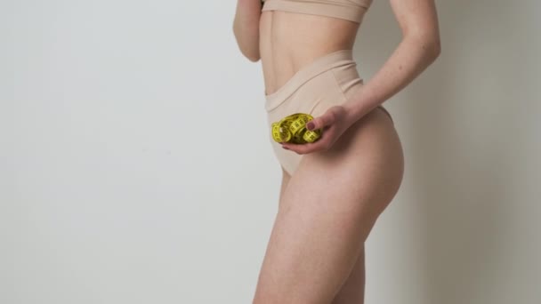 Porträt eines schlanken Mädchens in brauner Dessous, das nach Diät oder Sport seine Taille mit einem Maßband misst — Stockvideo