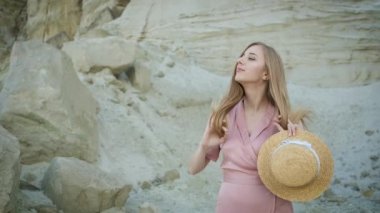 Kafkas görünümlü, pembe elbiseli, kapüşonlu sarışın genç bir turist kanyonun etrafında yürüyor ve kumların güzelliğinin tadını çıkarıyor.