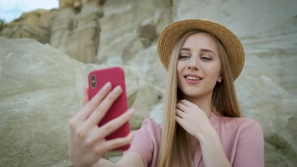 Junge kaukasische Touristin in rosa Kleid mit Kapuze hält ein rotes Telefon in der Hand und macht ein Selfie in der Schlucht mit schöner Aussicht — Stockvideo