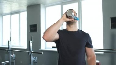 Spor salonundaki genç bir sporcu antrenmandan sonra su ve şişe içer.