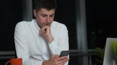 Kafkas görünümlü sevimli bir genç adam gece kadar ofiste oyalandı. Sosyal ağlarda oturup gülümsüyor.