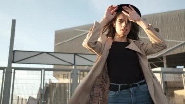 Genç ve güzel bir kız sokakta yürüyor. Siyah şapkalı, kahverengi pelerinli, uzun saçlı bir esmer. Arkadan portre çerçevesi