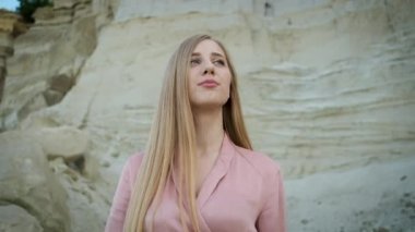Kafkas görünümlü, pembe elbiseli, kapüşonlu ve çantalı genç bir kadın kanyonda yürüyor ve kumların güzelliğinin tadını çıkarıyor.