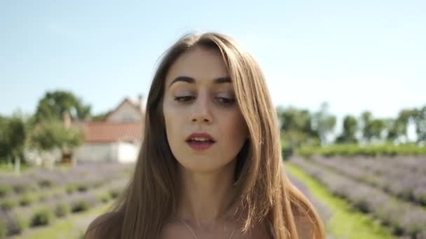 Ritratto di una bella ragazza bruna vestita di bianco con i capelli lunghi e un sorriso sincero che cammina su un campo di lavanda. Lavanda — Video Stock