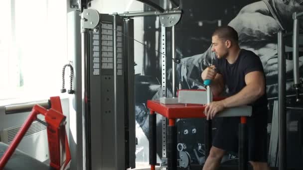 Un atleta sano entrena en una máquina de ejercicio en el gimnasio y se prepara para el amresling. Hombre azul caucásico. Deporte 07.05.2020 — Vídeo de stock