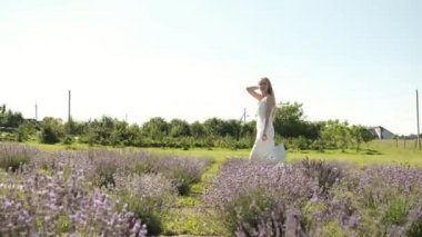 25 yaşında beyaz elbiseli güzel bir sarışın güneşli bir yaz akşamında elinde sepetle lavanta tarlasında yürüyor. Bir sürü mor çiçek. Arkadan. Lavanta