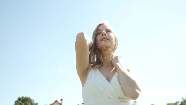 Běloch 25 let krásná blondýna v dlouhých bílých šatech procházky na levandulovém poli v letním slunném večeru. Spousta fialových květů — Stock video