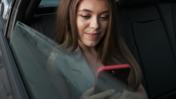 Mulher caucasiana bem sucedida em um terno elegante senta-se no carro e resolve problemas de trabalho pelo telefone — Vídeo de Stock