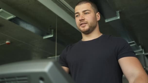Potret seorang pria atletik dengan bisep besar pemanasan di atas treadmill sebelum latihan di gym — Stok Video