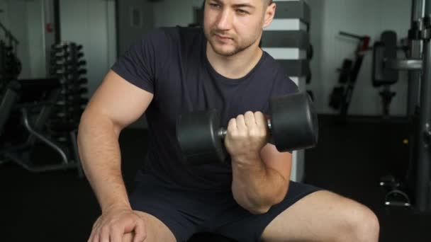 Здоровый накачанный спортсмен кавказской внешности и атлетическая фигура трясет бицепсами в тренажерном зале — стоковое видео