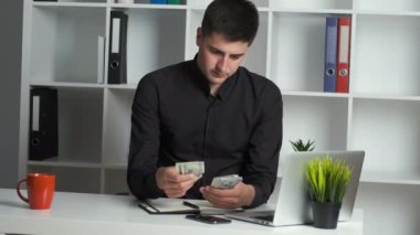 Keskin gözlü bir ofis çalışanı parayı sayar ve bir deftere yazar. Muhasebeci maaş veriyor.