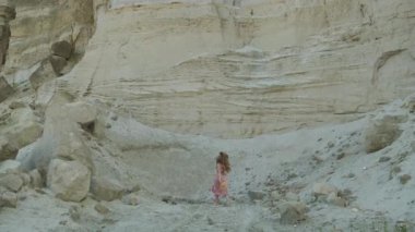 Güzel model sevinçle kum ocağının yakınında dönüyor. Kanyon. Sarı şapkalı, pembe elbiseli sarışın kız.