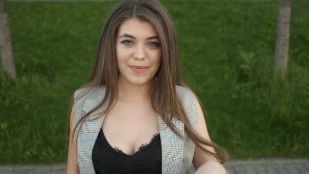 Schöne Mädchen von kaukasischem Aussehen mit einem aufrichtigen in einem grauen Anzug geht in der Nähe von modernen Büros — Stockvideo
