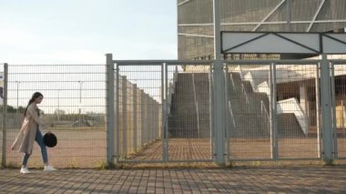 Güzel bir kız sokakta yürüyor ve şapkasını çıkarıp dönüyor. Siyah şapkalı, kahverengi pelerinli, uzun saçlı esmer kadın. Model kameranın önünde poz veriyor.