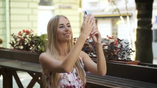 Γυναίκα τουρίστρια ξανθιά καυκάσια εμφάνιση περπατά γύρω από την πόλη πρωί σε ένα μακρύ φόρεμα και παίρνει φωτογραφίες των ιστορικών τόπων στο τηλέφωνο — Αρχείο Βίντεο