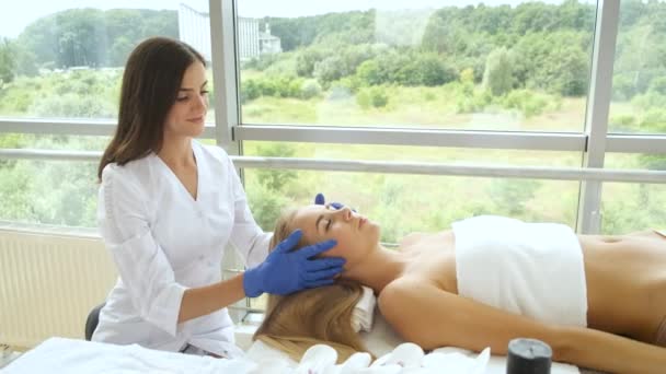 A mulher está a fazer uma massagem na cabeça num moderno spa com janelas panorâmicas. Saúde e autocuidado — Vídeo de Stock