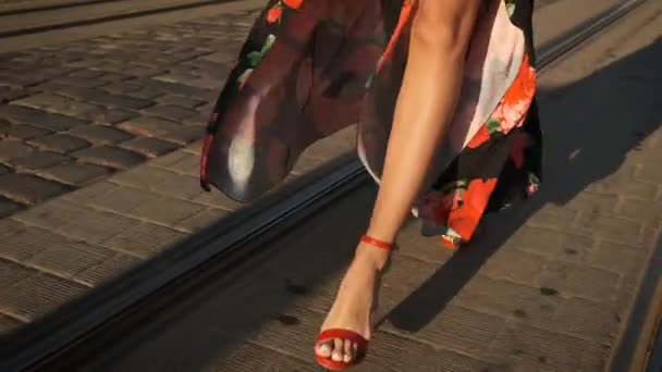 Модель с длинными ногами разгуливает по городу на каблуках в красных туфлях и длинном платье — стоковое видео