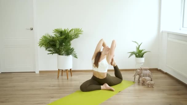 Een jonge blanke vrouw mediteert thuis. Yoga en fitness training. Stressverlichting. Gezondheid — Stockvideo