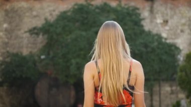 Beyaz görünümlü, samimi bir gülüşü, güzel uzun bir elbisesi ve siyah şapkası olan güzel bir sarışın sabah şehrinde dolaşıyor. Kameranın önünde poz veren bir turist. Model