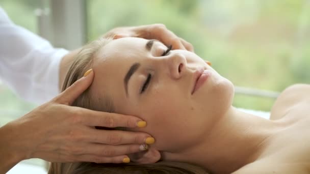 Mujer está teniendo un masaje en la cabeza en un moderno spa con ventanas panorámicas. Salud y autocuidado — Vídeos de Stock