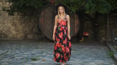 Beyaz görünümlü, samimi bir gülüşü, güzel uzun bir elbisesi ve siyah şapkası olan güzel bir sarışın sabah şehrinde dolaşıyor. Kameranın önünde poz veren bir turist. Model
