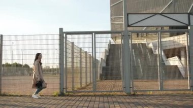 Güzel bir kız sokakta yürüyor ve şapkasını çıkarıp dönüyor. Siyah şapkalı, kahverengi pelerinli, uzun saçlı esmer kadın. Model kameranın önünde poz veriyor.