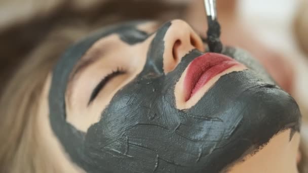 Mujer se encuentra sobre la mesa en un moderno spa y se relaja. Aplicar una máscara para rejuvenecer la piel. Salud y belleza — Vídeo de stock